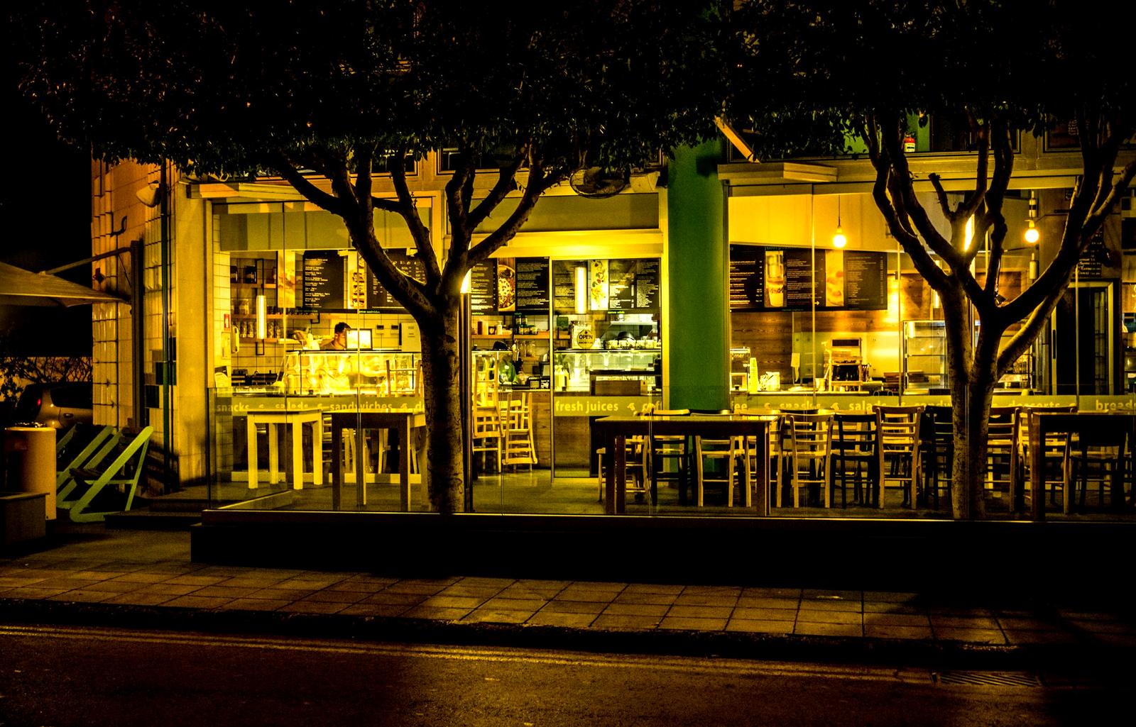 A warmly lit storefront cafe at night