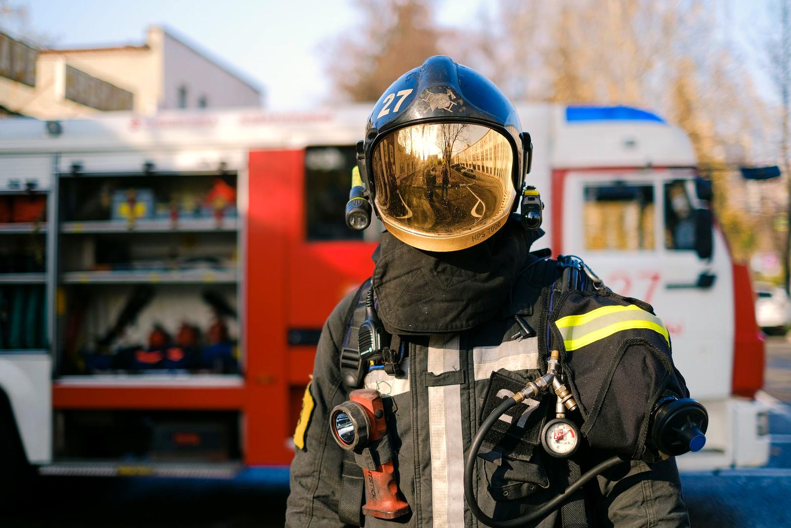 A firefighter in full gear standing in front of a fire truck