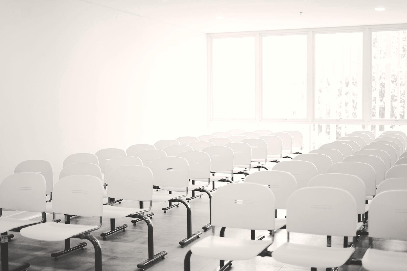 A bright meeting room with rows of white chairs